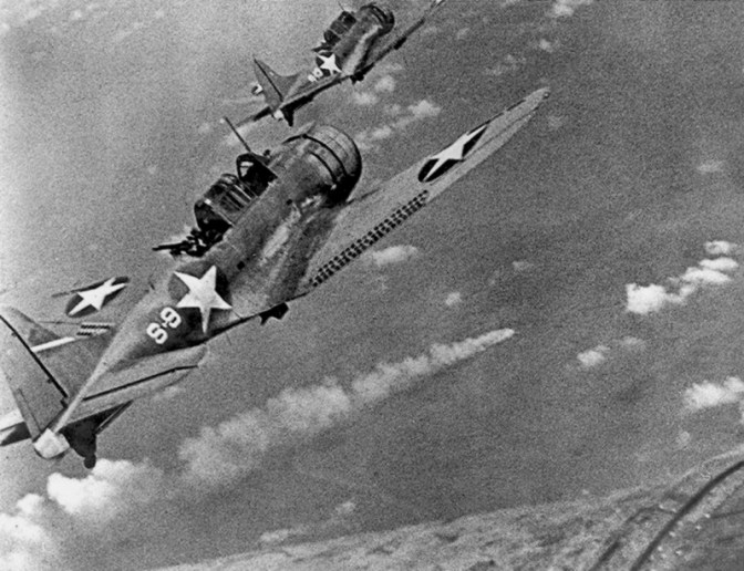 U.S. Navy Douglas SBD-3 "Dauntless" dive bombers from scouting squadron VS-8 from the aircraft carrier USS Hornet (CV-8) approaching the burning Japanese heavy cruiser Mikuma to make the third set of attacks on her, during the Battle of Midway, 6 June 1942. Mikuma had been hit earlier by strikes from Hornet and USS Enterprise (CV-6), leaving her dead in the water and fatally damaged. Note bombs hung beneath the SBDs. (US Navy Photograph) 